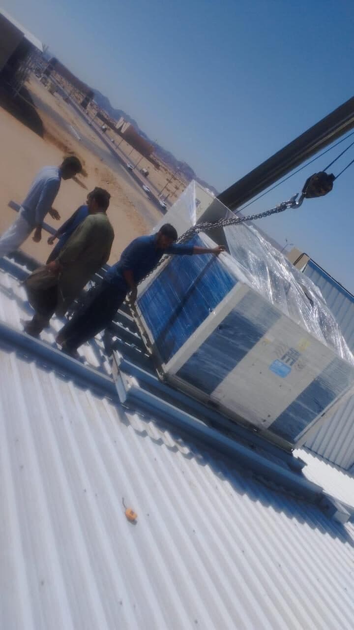 Crane lifting rooftop AC package unit