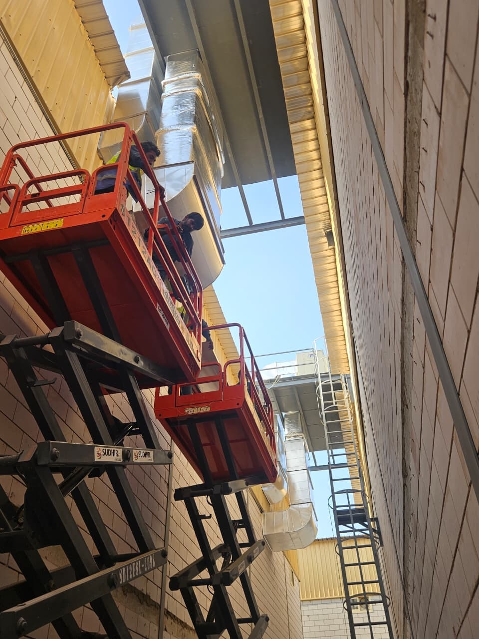 Technicians on scissor lifts wrapping insulated ductwork